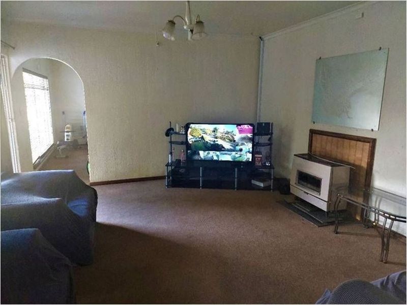 A living room featuring a built-in fireplace, arched doorway leading to an adjacent space, and carpeted flooring.