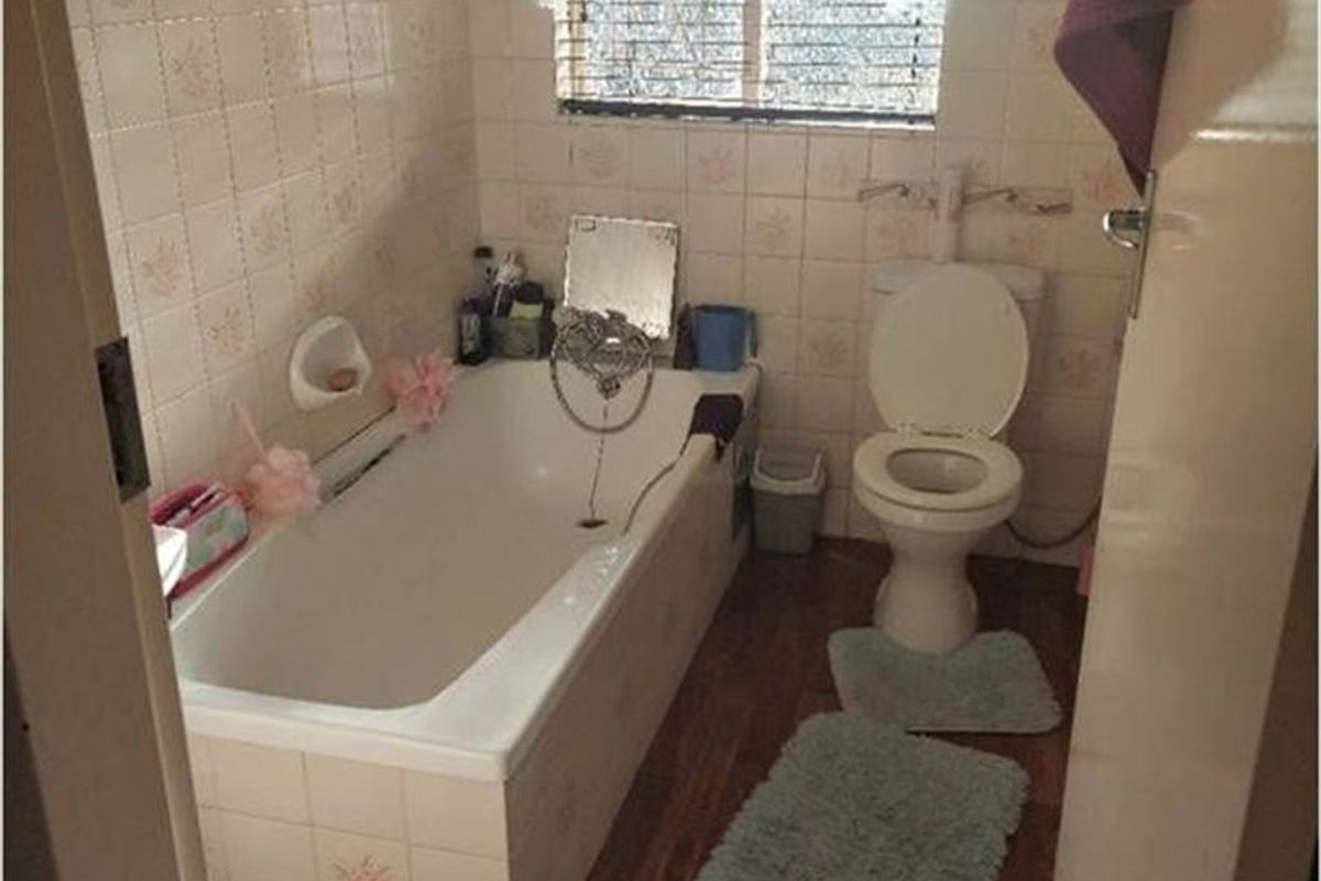 A dated bathroom featuring a standard bathtub, toilet, and tiled wall finishes, requiring modernization to improve its overall aesthetic and functionality.