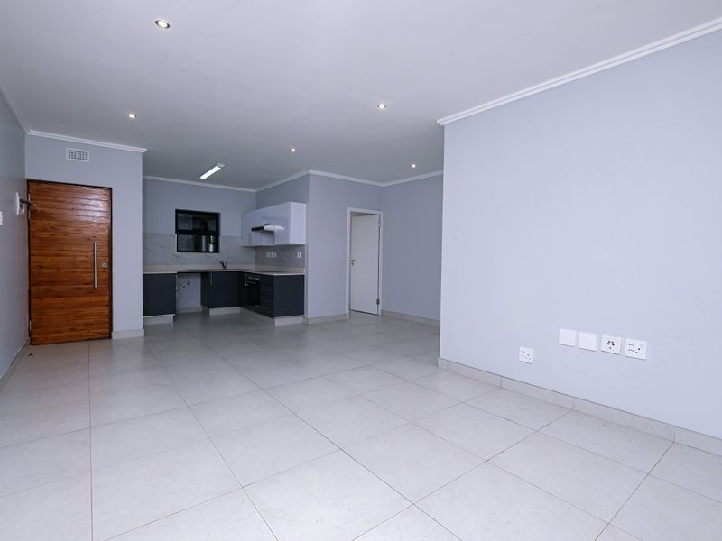Spacious open-plan living area featuring tiled floors, recessed lighting, and a modern kitchen with built-in cabinetry, oven, and extractor fan.