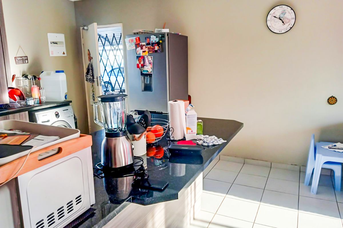 A functional kitchen area featuring a granite breakfast bar, tiled flooring, and built-in cabinetry, providing a practical space for daily meal preparation.