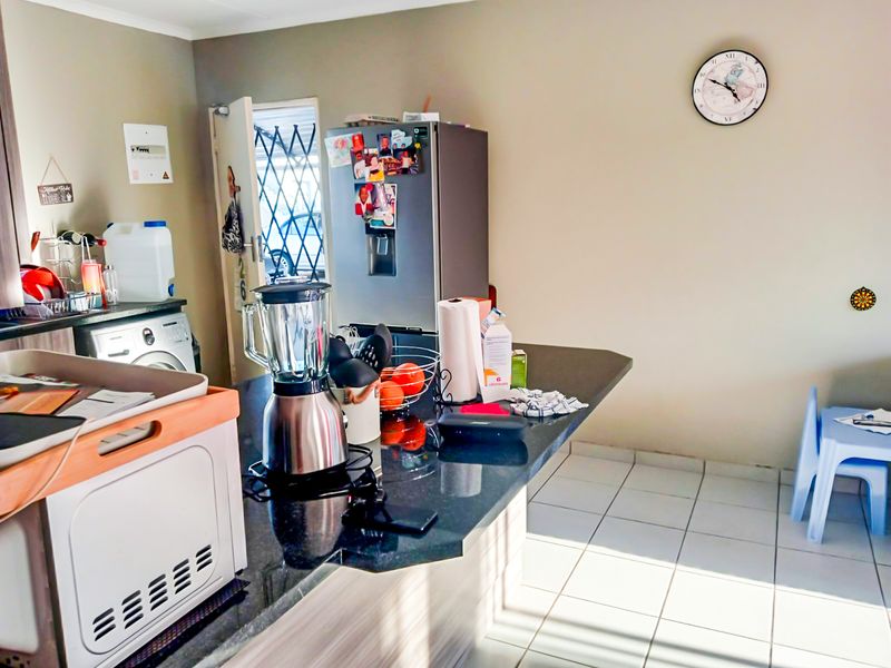 A functional kitchen area featuring a granite breakfast bar, tiled flooring, and built-in cabinetry, providing a practical space for daily meal preparation.