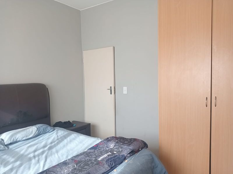 A bedroom featuring neutral wall tones and a functional built-in wooden wardrobe, providing essential storage space.