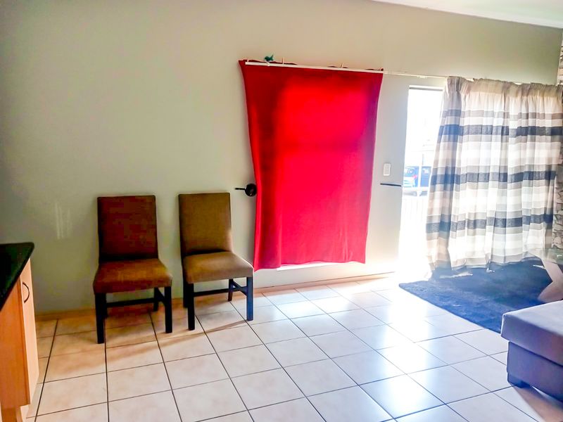 An open-plan living area featuring tiled flooring and a sliding door providing access to the exterior.