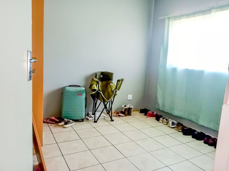A simple, vacant bedroom featuring neutral wall paint and tiled flooring, offering a blank canvas for potential interior design and furnishing.