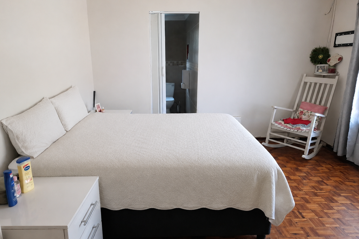 A bedroom featuring parquet flooring and direct access to an en-suite bathroom via a folding door.