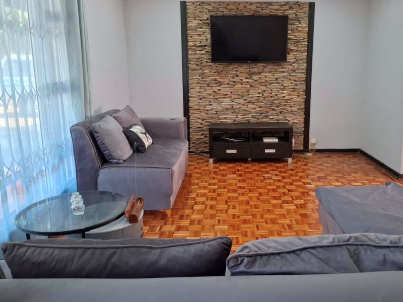 A comfortable living room featuring classic parquet flooring and a decorative stone feature wall, providing a warm and inviting atmosphere.