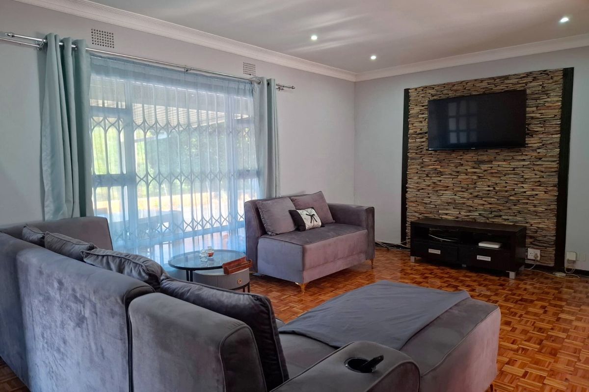 A well-maintained living room featuring classic parquet flooring, a textured stone feature wall, and recessed lighting, creating a warm and inviting atmosphere.