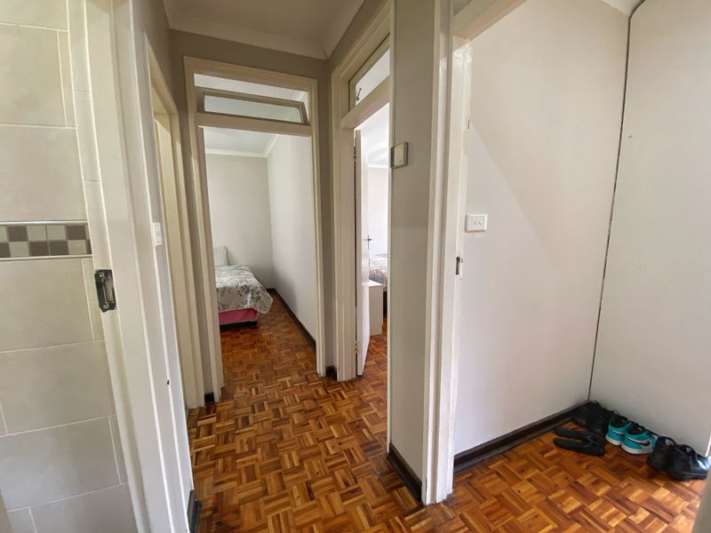 A functional hallway featuring classic parquet flooring and multiple doorways leading to adjacent rooms, providing a central circulation space within the home.