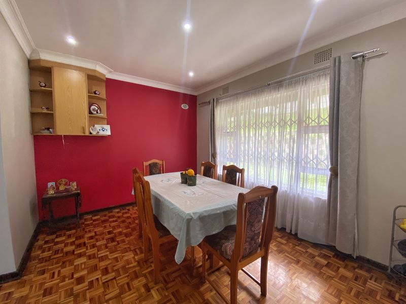 Dining room featuring classic parquet flooring, recessed downlighting, and built-in wall shelving, with a large window fitted with a security gate.