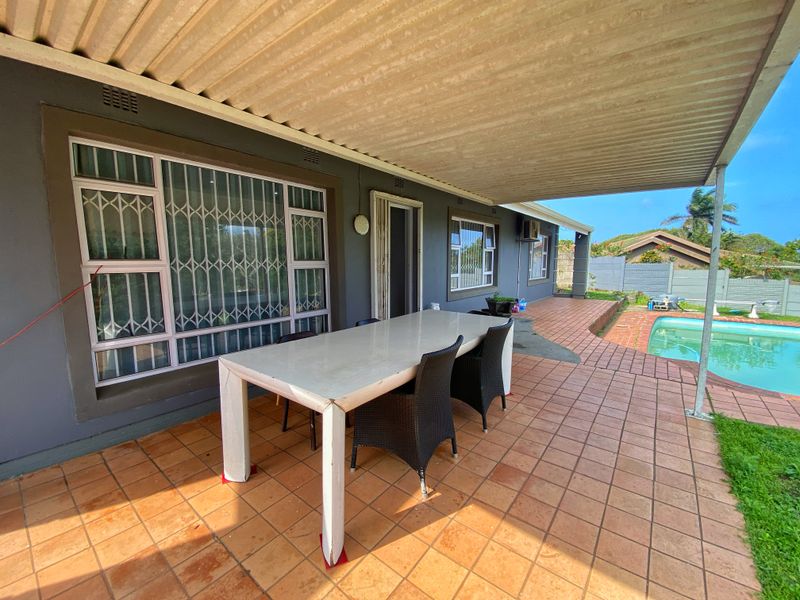 A covered outdoor patio area featuring tiled flooring and direct access to the swimming pool, providing a functional space for outdoor entertaining.