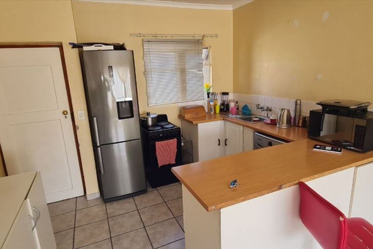 A functional kitchen featuring built-in cabinetry, laminate countertops, a breakfast bar, and tiled flooring, offering a practical layout for daily use.