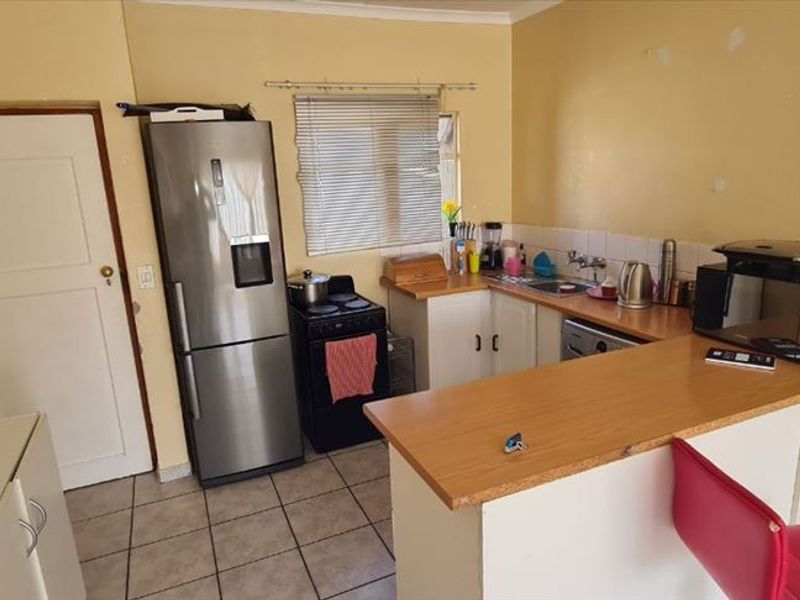 A functional kitchen featuring built-in cabinetry, laminate countertops, a breakfast bar, and tiled flooring, offering a practical layout for daily use.