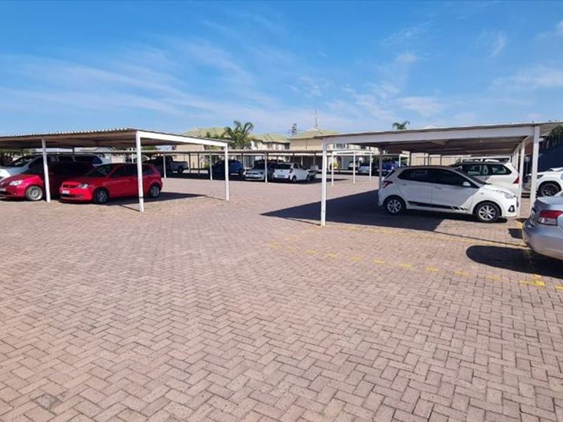 An open-air parking area featuring paved ground surfaces and multiple covered carport structures for resident vehicle storage.