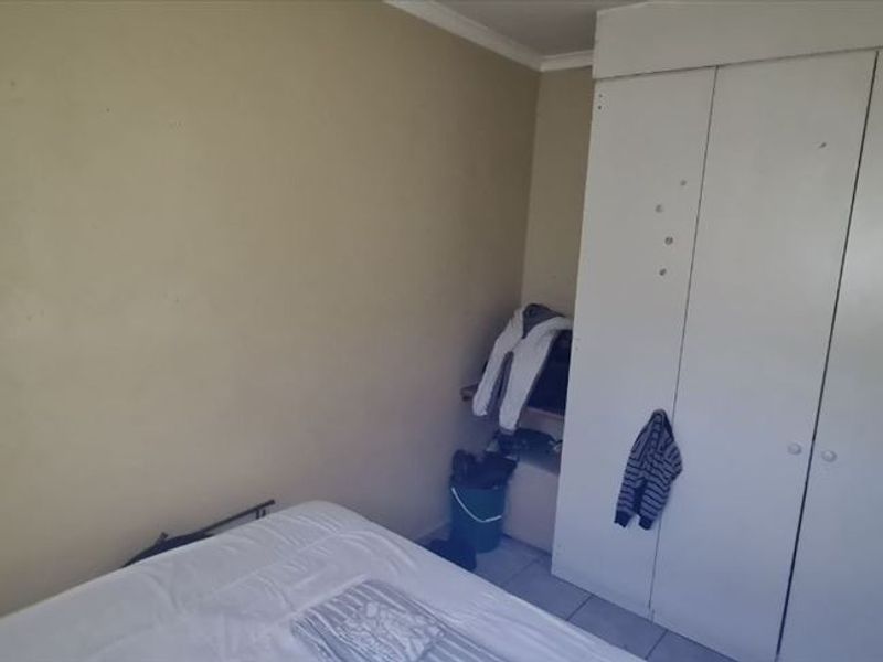 A bedroom featuring a built-in wardrobe and tiled flooring, requiring cosmetic updates to the wall finishes.