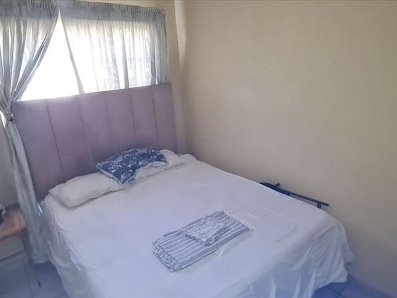 A compact bedroom featuring tiled flooring and neutral wall finishes, offering a functional space that could benefit from cosmetic updates.