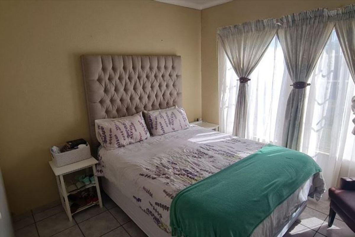 A bedroom featuring tiled flooring and large windows with curtain rails, providing natural light and a functional layout.