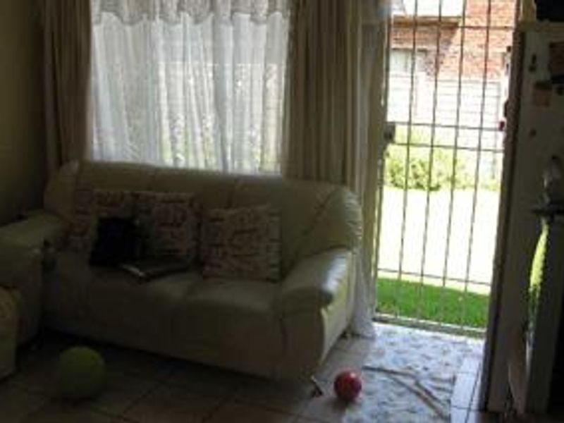 A living room area featuring tiled flooring and a security gate leading to the exterior garden space.