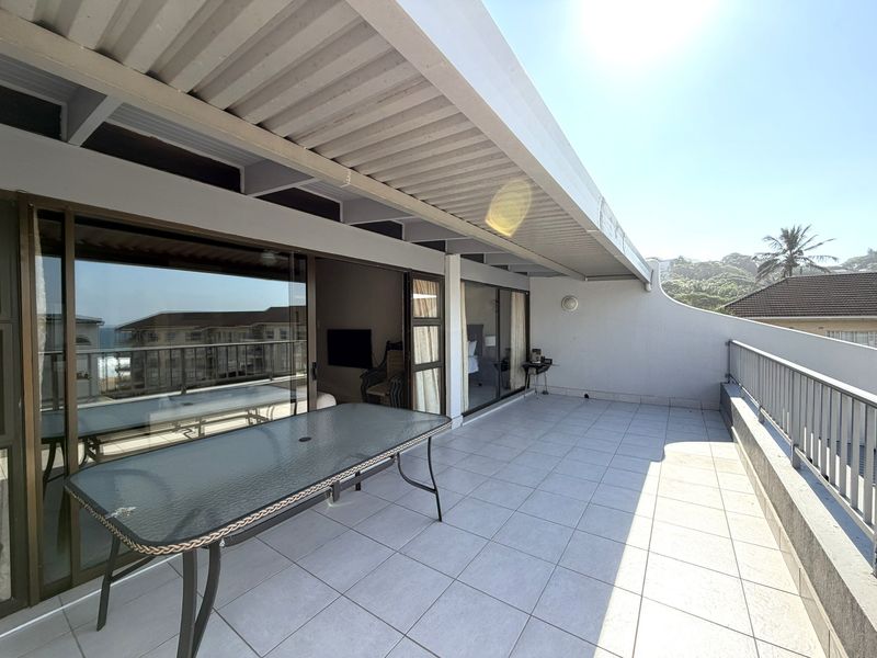 Spacious covered balcony featuring tiled flooring, metal balustrades, and large sliding glass doors providing seamless indoor-outdoor flow.