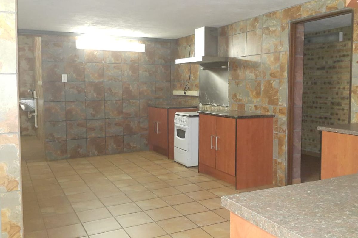 A dated kitchen featuring tiled walls, built-in cabinetry, and a freestanding stove, offering a functional layout ready for modernization.