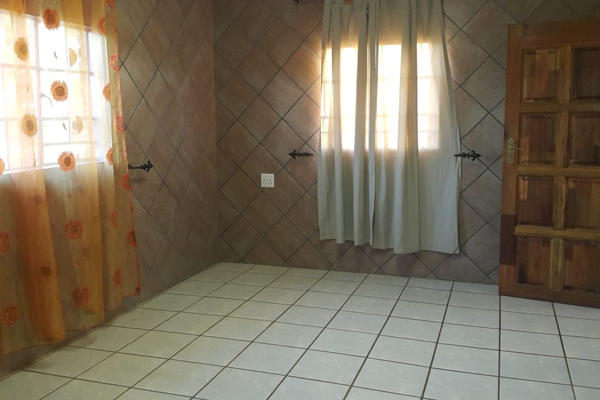 An empty bedroom featuring tiled walls and ceramic floor tiles, offering a blank canvas for potential interior updates and modernization.