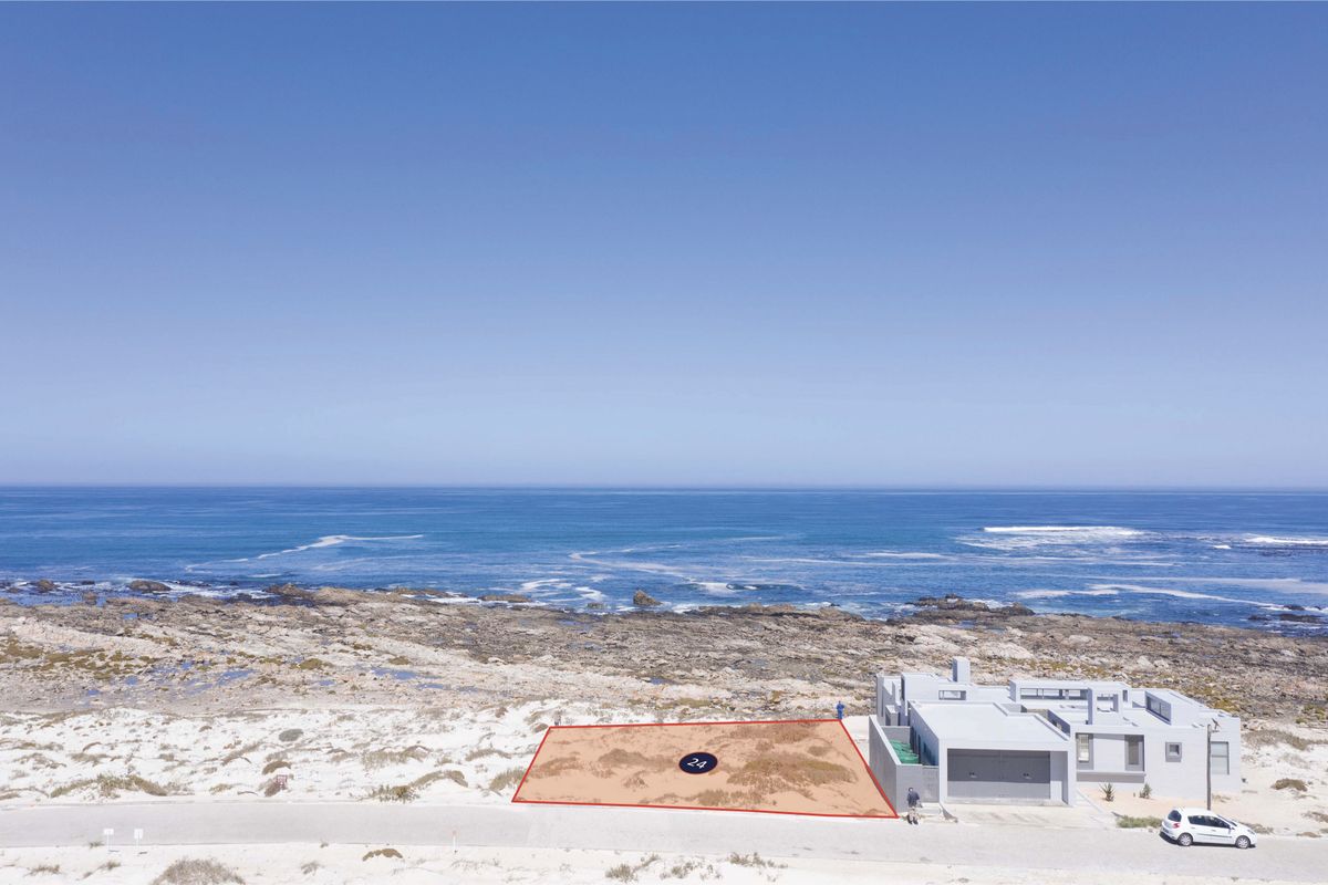 An aerial view of a vacant residential plot situated directly along the coastline, offering prime ocean views and beach access.