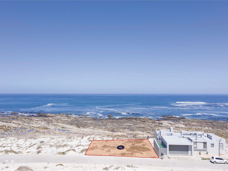 An aerial view of a vacant residential plot situated directly along the coastline, offering prime ocean views and beach access.
