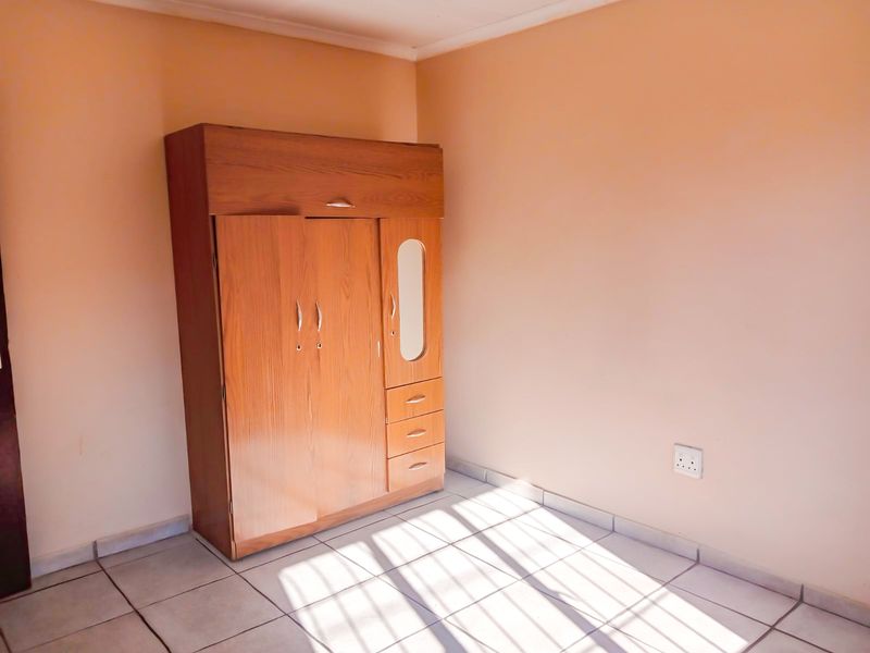 A simple bedroom featuring tiled flooring and a neutral wall finish, providing a clean and functional space.