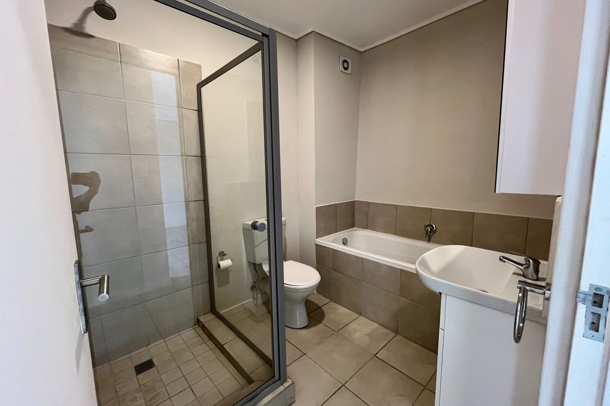 A clean, functional bathroom featuring a separate shower enclosure, a bathtub, and a pedestal basin with neutral wall and floor tiling.