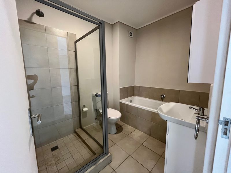 A clean, functional bathroom featuring a separate shower enclosure, a bathtub, and a pedestal basin with neutral wall and floor tiling.