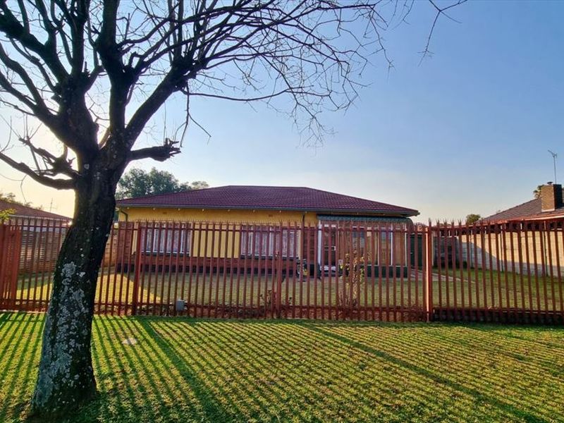 Front view of a single-story residential house featuring a tiled roof, plastered exterior walls, and secure metal palisade fencing surrounding the property.