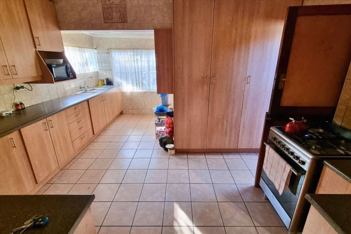 A functional kitchen featuring laminate cabinetry, tiled flooring, a gas stove, and ample storage space with a built-in pantry cupboard.