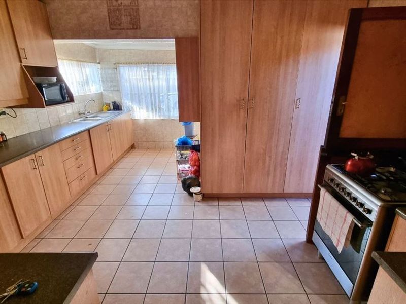 A functional kitchen featuring laminate cabinetry, tiled flooring, a gas stove, and ample storage space with a built-in pantry cupboard.