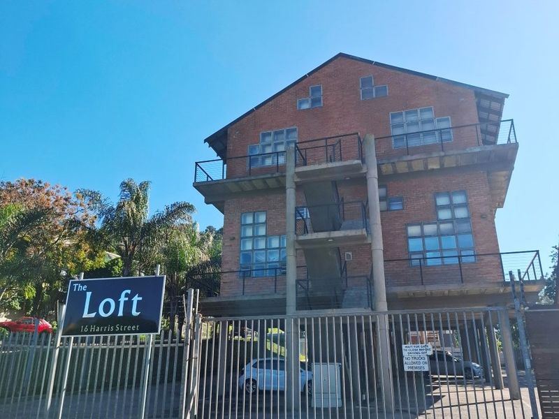 Front exterior view of The Loft apartment building, featuring a brick facade, metal security gate, and external staircase access.
