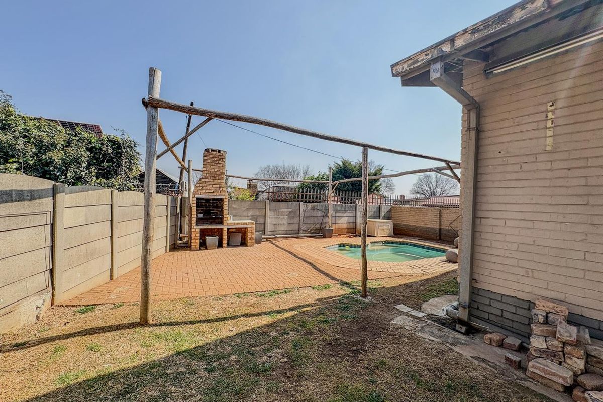 Rear garden area featuring a swimming pool, paved patio, and a brick built-in braai, enclosed by precast concrete boundary walls.