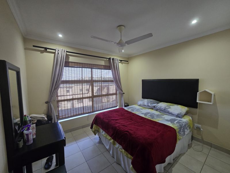 A functional bedroom featuring tiled flooring, a ceiling fan, recessed lighting, and window blinds, providing a comfortable and well-lit living space.