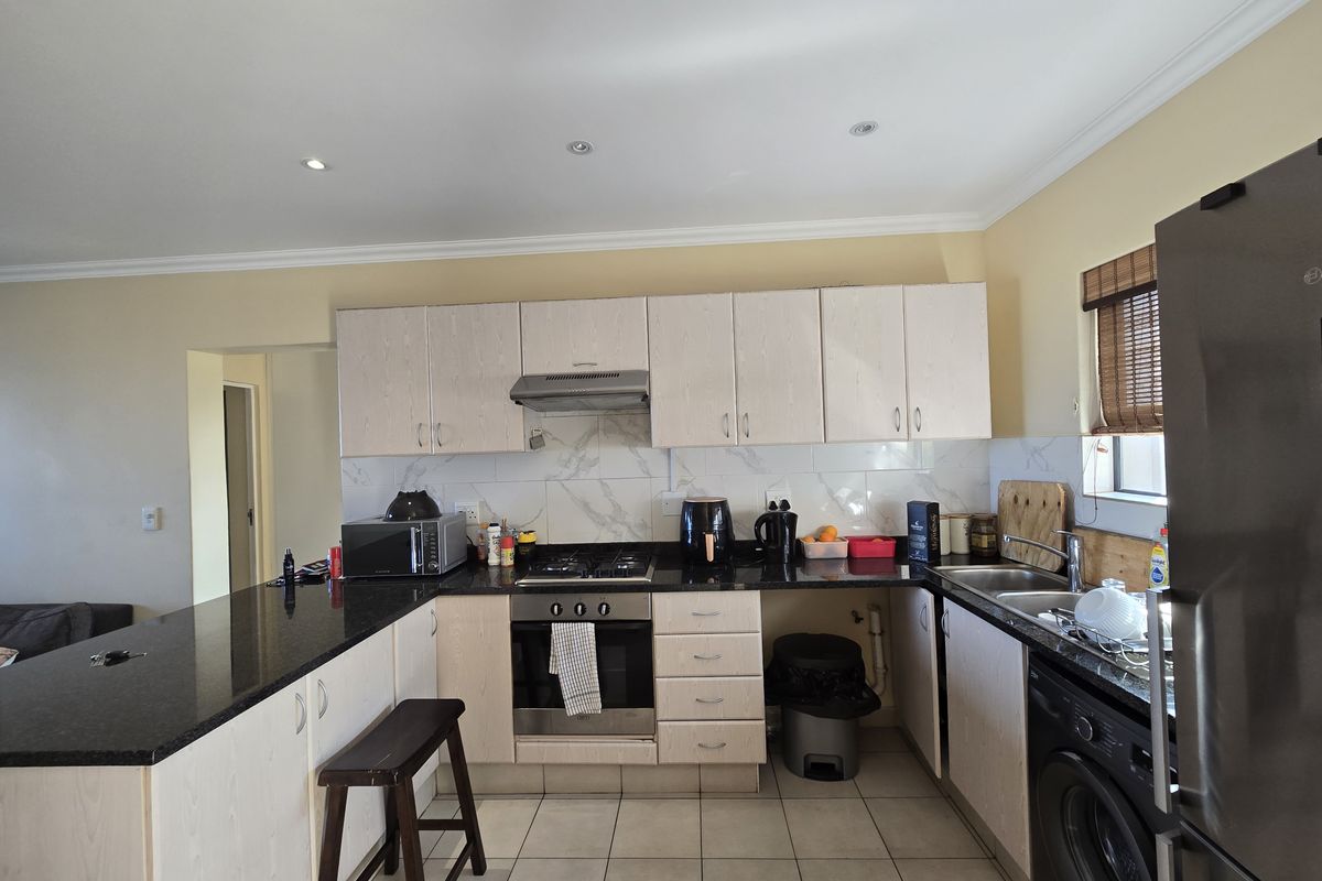 Functional kitchen featuring granite countertops, built-in oven, gas hob, and marble-look splashback tiles, offering a practical layout for daily cooking and meal preparation.