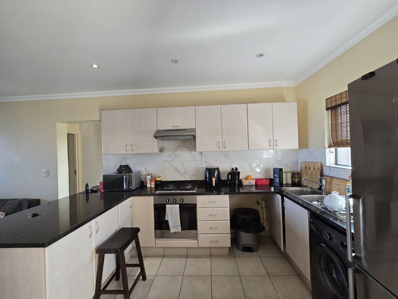 Functional kitchen featuring granite countertops, built-in oven, gas hob, and marble-look splashback tiles, offering a practical layout for daily cooking and meal preparation.