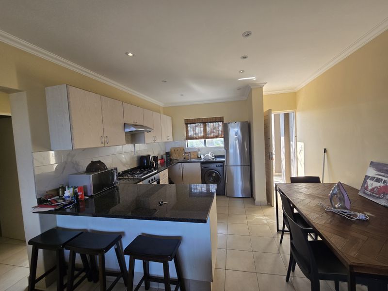 Open-plan kitchen and dining area featuring granite countertops, built-in cabinetry, gas hob, and tiled flooring, providing a functional space for cooking and dining.