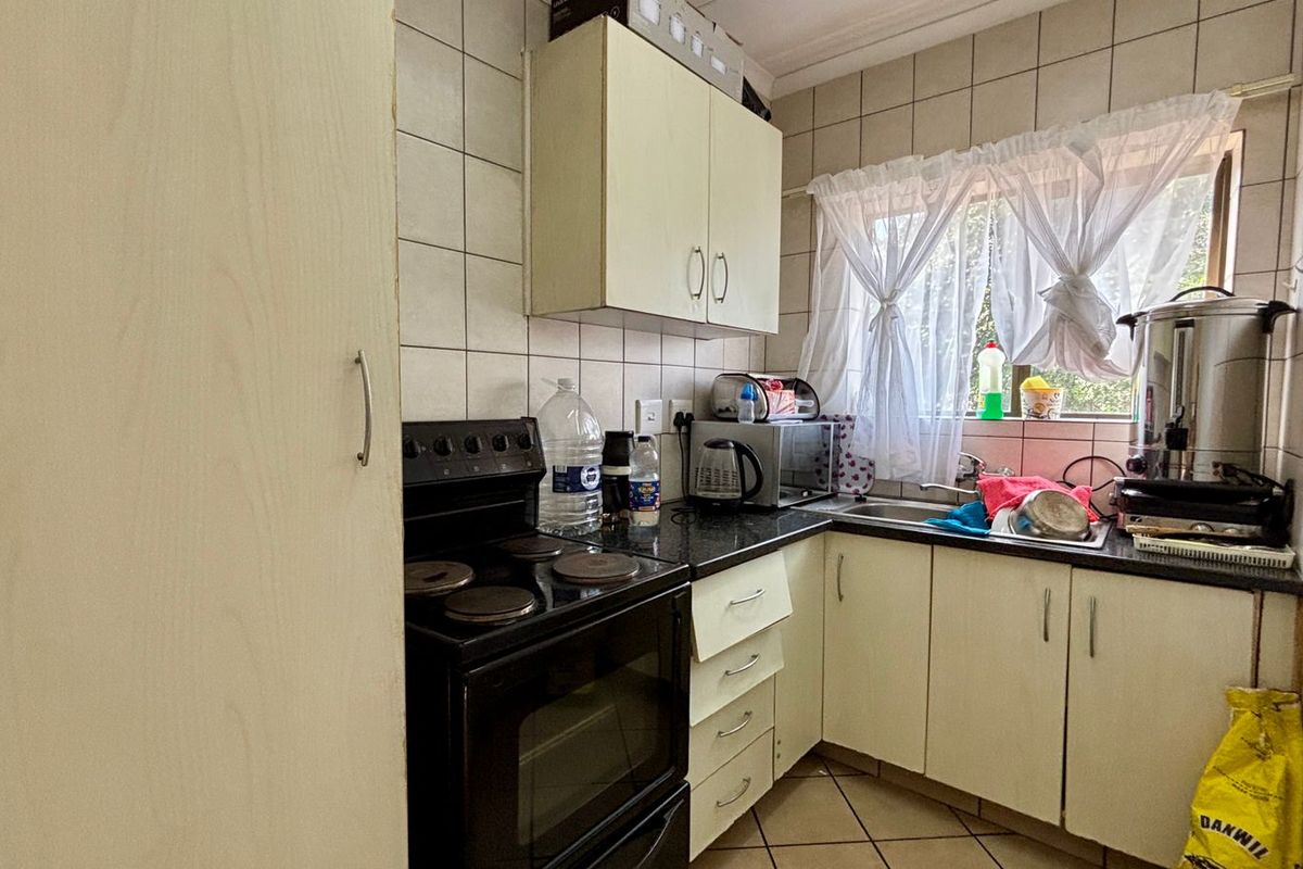A compact kitchen featuring built-in cabinetry, tiled backsplash, and a stainless steel sink, offering a functional layout with potential for modern updates.