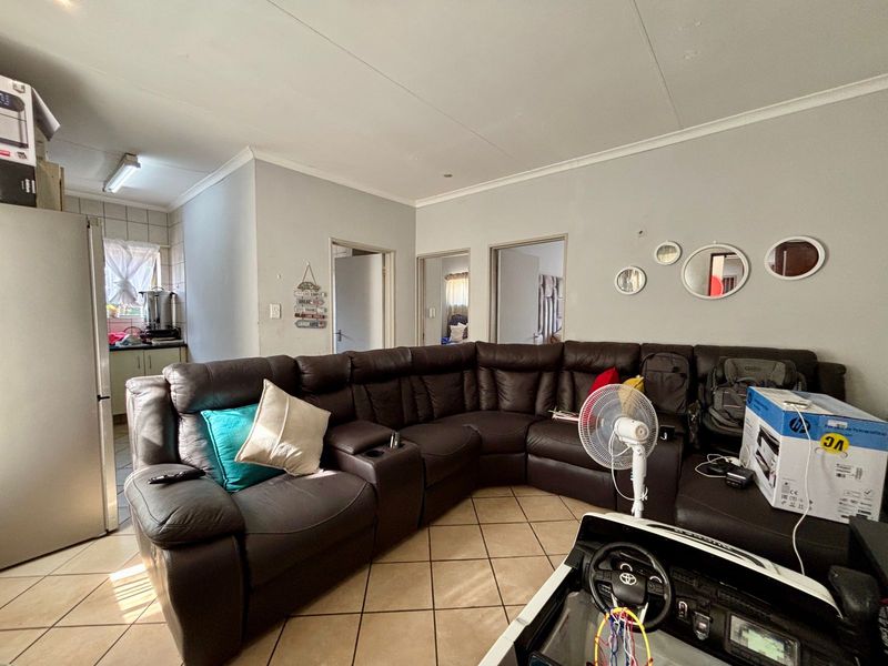 Open plan living area featuring tiled flooring and coved ceilings, seamlessly connecting to the adjacent kitchen and hallway access points.