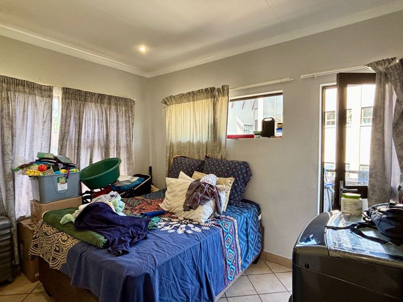 A bedroom featuring tiled flooring, cove cornicing, and a glass panel door leading to an outdoor area.