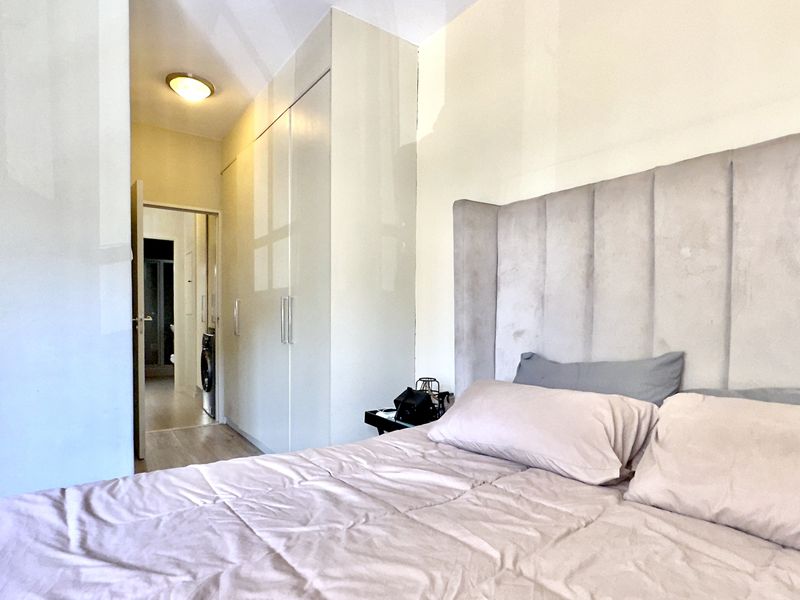 A well-maintained bedroom featuring built-in cupboards and direct access to an adjoining bathroom area.