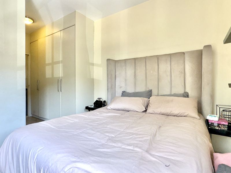 A well-maintained bedroom featuring built-in cupboards and neutral finishes, providing a clean and functional sleeping space.