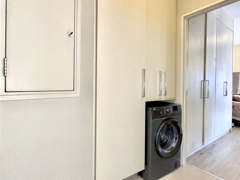 A functional laundry area featuring built-in cabinetry and integrated appliance connections, providing efficient storage and utility space within the apartment.
