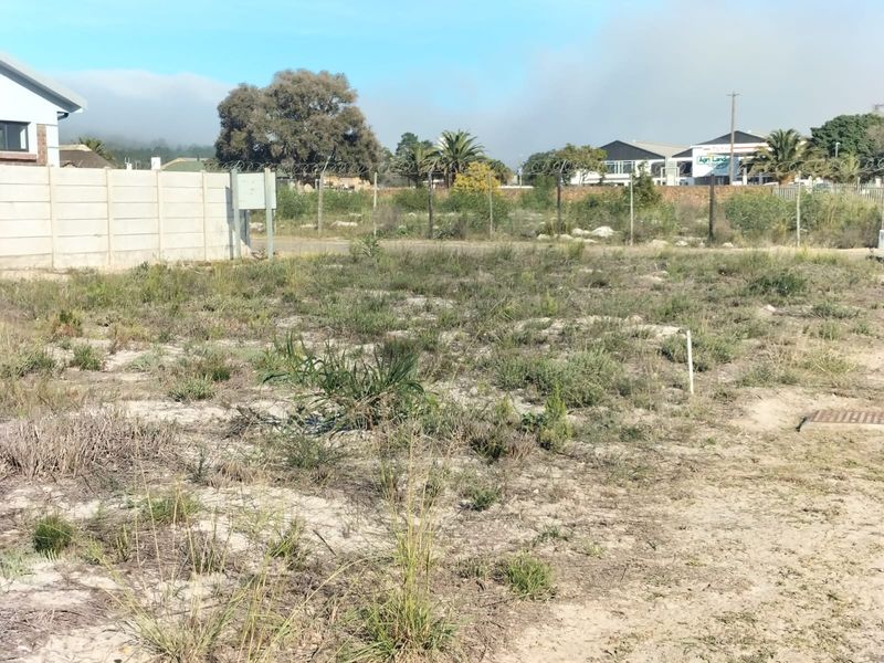 A vacant residential plot featuring a precast concrete boundary wall with security fencing and natural vegetation.