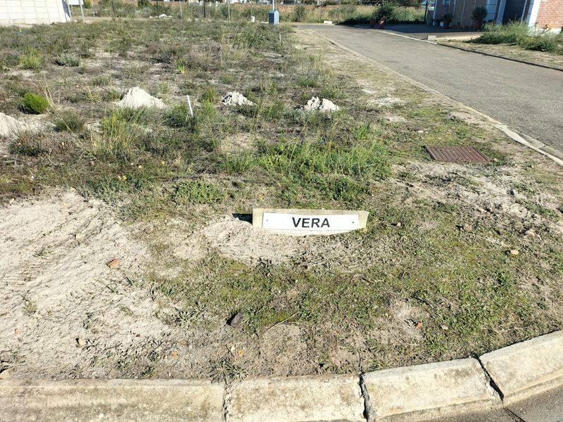 A view of a vacant residential plot featuring a property marker, concrete curbing, and access to a paved street.