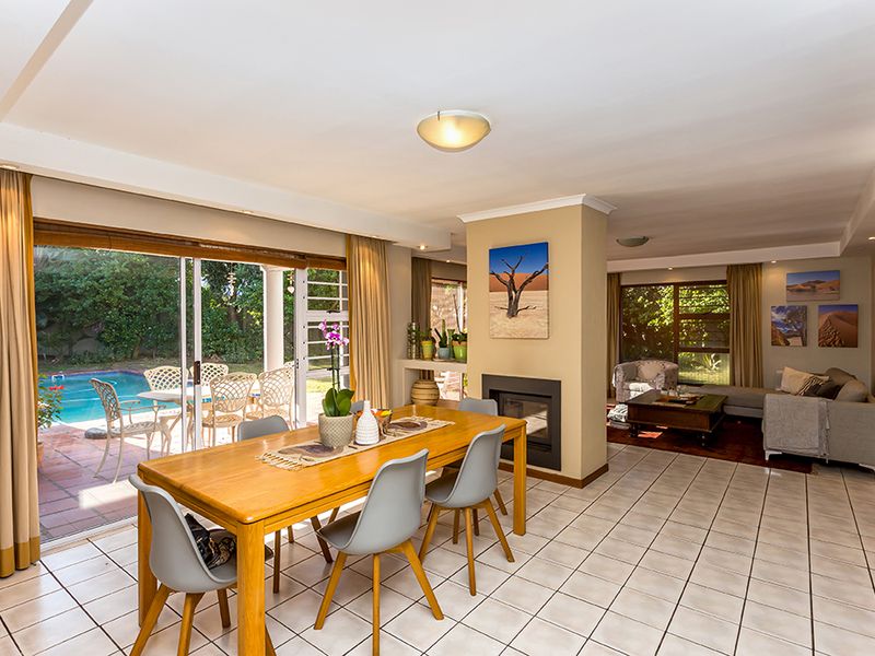 Spacious open-plan living and dining area featuring tiled floors, a built-in fireplace, and large sliding doors providing seamless access to the outdoor pool area.