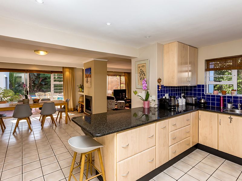 Open-plan kitchen and dining area featuring granite countertops, light wood cabinetry, tiled flooring, and direct access to the outdoor patio through sliding glass doors.