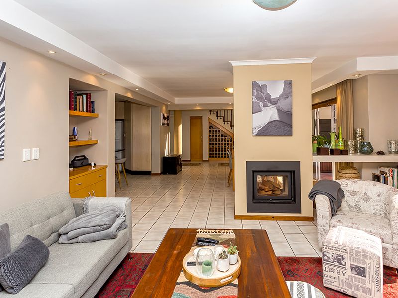 Spacious open-plan living area featuring a central built-in fireplace, tiled flooring, and recessed shelving, creating a warm and functional multi-purpose space.