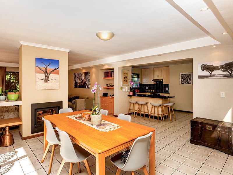 Open-plan living and dining area featuring a built-in fireplace, tiled flooring, and a functional kitchen with granite countertops and a breakfast bar.